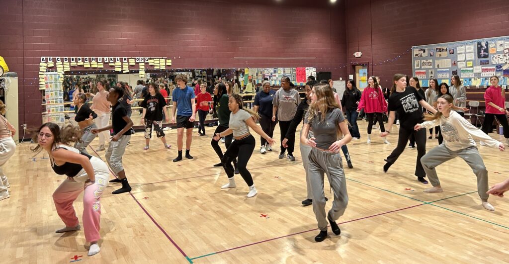 The Carole Cascio Fund’s Teaching Artist Adrienne Klaus Latanishen was brought in to teach a special combined Hip Hop master class for Queen Anne’s County High School (QACHS) dancers with students from Centreville Middle School (CMS). Michael Bell, Supervisor of Instruction for QACPS and Carole Cascio Fund Executive Director Peter Pucci worked closely with QACHS Dance Teacher Kristen Tyler to help coordinate so CMS and QACHS students could participate in the combined Hip-Hop class. The class was conceived to help funnel interested dance students into the dance program at QACHS directed by Ms. Tyler. CMS Principal Tracy Kenna coordinated with Ms. Tyler and put together 30 interested students. Principal Kenna worked out all the necessary the details with choir teacher Lucas O’ Farrell Principal Kenna walked the students over from CMS to the high school and met Ms. Tyler in the high school’s large dance studio. Adrienne prepared a vigorous class and worked with all the students together. She also worked individually with the middle school students and the high school students so they could watch each other and learn from each other. The CMS students were very excited and happy they could participate in the master class with the high school dancers. It was a lively and fun atmosphere with over 45 students combined in the class. After the class was over Ms. Tyler took a poll to see how many CMS students were interested in the dance and the athletic movement classes. There was an enthusiastic and positive response from a large number of students to participate in the dance and movement classes.